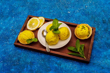 Lemon ice cream with mint. Refreshing summer dessert, ripe fruit, fragrant leaves. Navy blue nautical background, copy spaceの写真素材