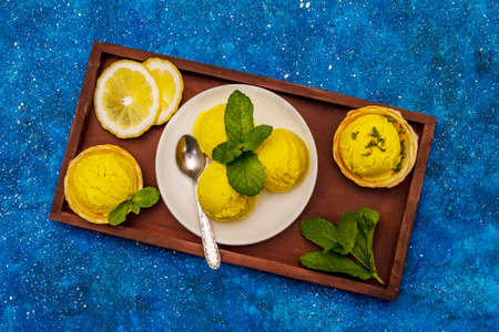 Lemon ice cream with mint. Refreshing summer dessert, ripe fruit, fragrant leaves. Navy blue nautical background, top viewの写真素材
