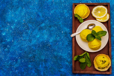 Lemon ice cream with mint. Refreshing summer dessert, ripe fruit, fragrant leaves. Navy blue nautical background, top viewの写真素材