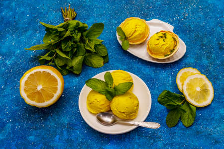 Lemon ice cream with mint. Refreshing summer dessert, ripe fruit, fragrant leaves. Navy blue nautical background, close upの写真素材