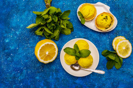 Lemon ice cream with mint. Refreshing summer dessert, ripe fruit, fragrant leaves. Navy blue nautical background, top viewの写真素材