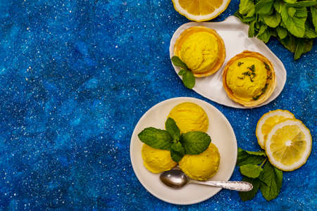 Lemon ice cream with mint. Refreshing summer dessert, ripe fruit, fragrant leaves. Navy blue nautical background, top viewの写真素材