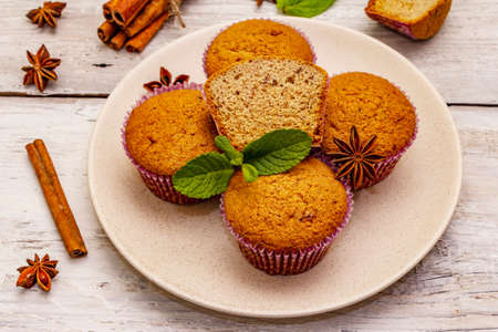 Homemade cupcakes with cinnamon, star anise and fresh mint. Autumn good mood, warm weather. Old wooden boards background, close upの写真素材