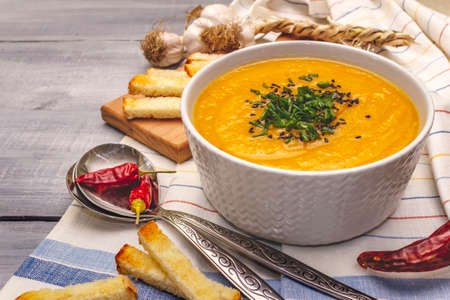 Vegetable cream soup. Healthy vegan (vegetarian) nutrition concept. Garlic, croutons, spices, aromatic seasonings. Wooden boards background, copy spaceの写真素材