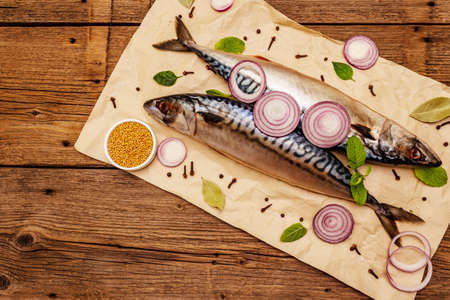 Pickled whole mackerel. Traditional Norwegian spicy salting fish. Spices, Dijon mustard, onions. Old wooden boards background, top viewの写真素材