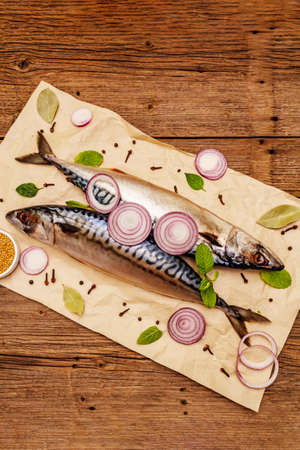 Pickled whole mackerel. Traditional Norwegian spicy salting fish. Spices, Dijon mustard, onions. Old wooden boards background, top viewの写真素材