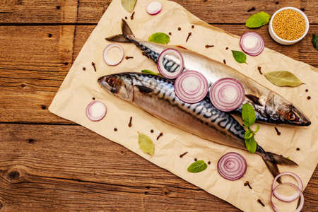 Pickled whole mackerel. Traditional Norwegian spicy salting fish. Spices, Dijon mustard, onions. Old wooden boards background, top viewの写真素材