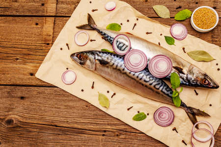 Pickled whole mackerel. Traditional Norwegian spicy salting fish. Spices, Dijon mustard, onions. Old wooden boards background, top viewの写真素材