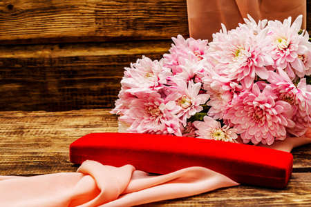Bouquet of gently pink chrysanthemums and jewelry. Beautiful gift on vintage wooden background. Romantic mood concept, copy spaceの写真素材