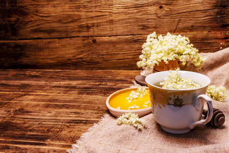 Tea from fresh elder flowers. Hot drink, honey, alternative medicine. Old wooden boards background, copy spaceの写真素材