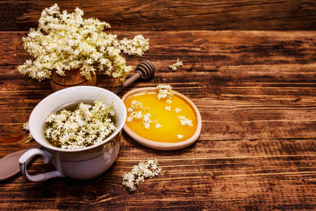Tea from fresh elder flowers. Hot drink, honey, alternative medicine. Old wooden boards background, copy spaceの写真素材