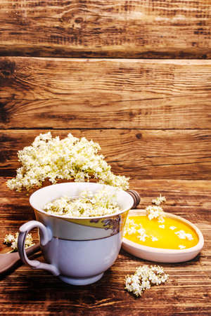 Tea from fresh elder flowers. Hot drink, honey, alternative medicine. Old wooden boards background, copy spaceの写真素材