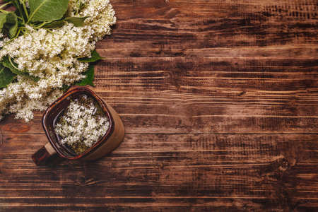 Tea from fresh elder flowers. Hot drink, alternative medicine. Old wooden boards background, top viewの写真素材