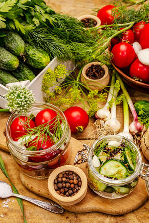 Pickling vegetables concept. Cooking process, spices, fresh fragrant herbs. Ripe tomatoes and cucumbers, old wooden tableの写真素材
