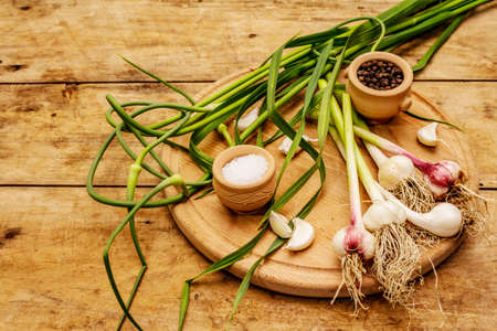 Set of ingredients for pickling garlic arrows. Ripe vegetables, herbs, sea salt, spices. Old wooden table, cutting boardの写真素材