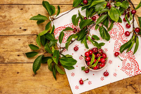 Ripe cherries in bowl and on the branches. Fresh berries, healthy dessert. Old wood plank background