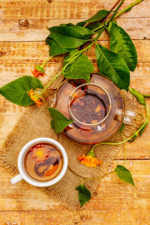 Fresh marigold flowers tea. Alternative medicine, wooden boards background, top viewの写真素材