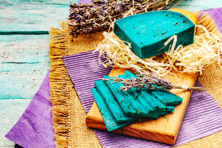 Dutch blue cheese with lavender. Piece and slices, dry fragrant flower, cutting board. Trendy turquoise wooden boards background, copy spaceの写真素材