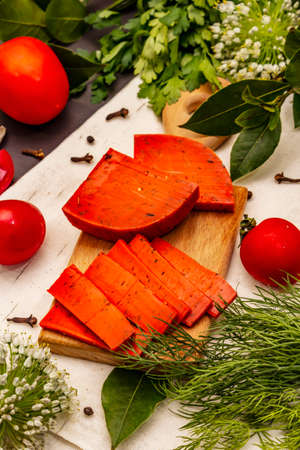 Dutch gouda pesto red cheese. Ripe tomatoes, fresh herbs, fragrant spices. Black stone concrete background, close upの写真素材