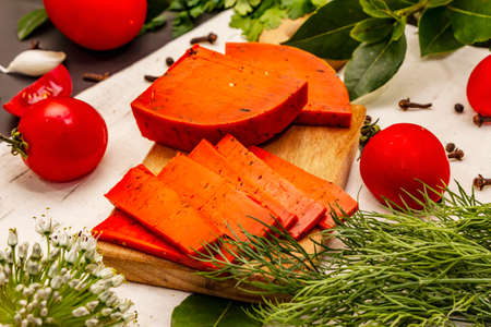 Dutch gouda pesto red cheese. Ripe tomatoes, fresh herbs, fragrant spices. Black stone concrete background, close upの写真素材