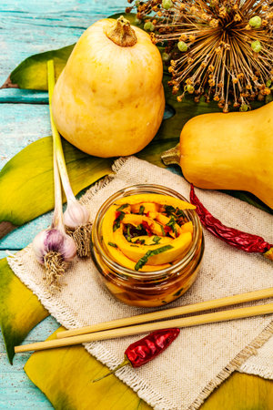 Hobak pumpkin kimchi. Korean traditional savory food. Spicy marinated pieces, fragrant spices, fresh vegetables. Trendy turquoise wooden boards background, close upの写真素材