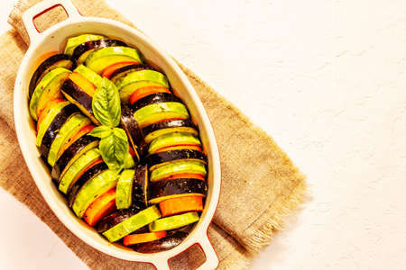Fresh vegetables for baking. Olive oil, eggplant, zucchini, carrot, spices and basil. White putty background, top viewの写真素材