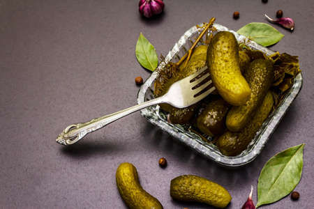 Marinated pickled cucumbers with spices and herbs. Traditional fermented appetizer in glass jar. Wooden boards background, top viewの写真素材