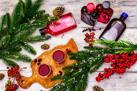 Festive berries liqueur or tincture in double-walled glasses. Ingredient for preparation alcohol cocktail. New Year or Christmas design, white wooden boards background, top viewの写真素材