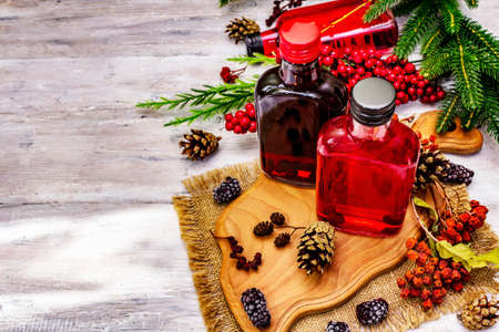 Festive berries liqueur or tincture. Ingredient for preparation alcohol cocktail. New Year or Christmas design, white wooden boards background, copy spaceの写真素材