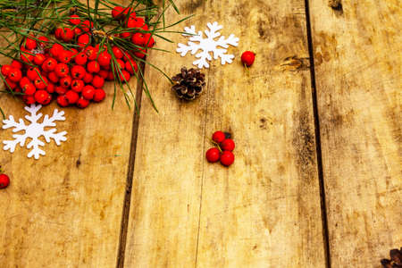 Christmas or New Year concept. Fresh pine branches, ripe rowan berries, snowflakes and pine cones. Old wooden background, copy spaceの写真素材