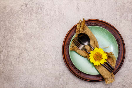 Autumn and Thanksgiving dinner place setting. Sunflower bouquet, ceramic plates and sackcloth...