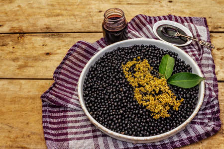 Elderberry jam, syrup or confiture. Fresh ripe berries, healthy sweet dessert. Alternative medicine and lifestyle. Old wooden table, copy spaceの写真素材