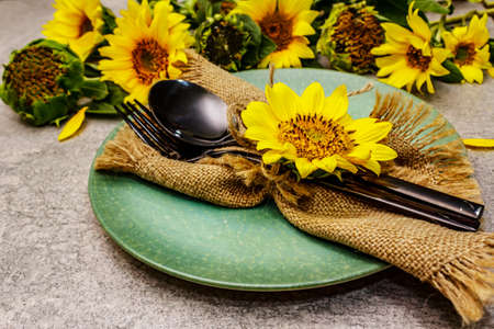 Autumn and Thanksgiving dinner place setting. Sunflower bouquet, ceramic plate and sackcloth napkin....
