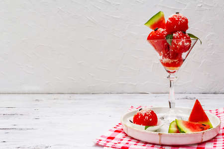 Sweet watermelon ice cream with coconut flakes and fresh basil leaves. Healthy dessert, white wooden boards background, copy spaceの写真素材