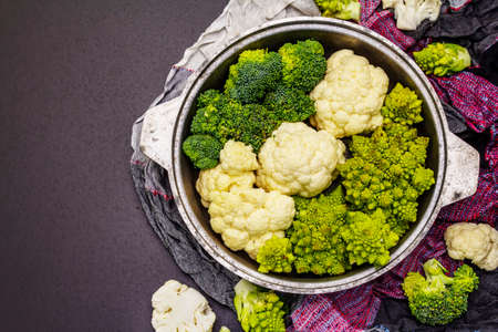 Assorted broccoli, romanesco and cauliflower. Fresh ripe ingredient for healthy food. Black stone concrete background, top viewの写真素材