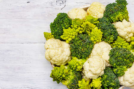 Assorted broccoli, romanesco and cauliflower. Fresh ripe ingredient for healthy food. White wooden boards background, close upの写真素材