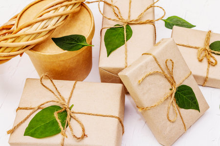 Zero waste gift concept. Creative arrangement frame of craft boxes and green leaves on white putty...