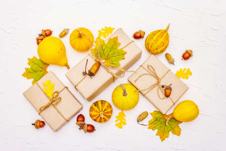Zero waste gift concept, no plastic life style. Creative autumn decor with paper boxes, mini pumpkins, acorns and fall leaves. Thanksgiving or Halloween concept on white putty background, top viewの写真素材