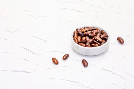 Dry brown bean or kidney bean in glass jar. A valuable source of protein for a healthy vegan diet. White putty background, copy spaceの写真素材