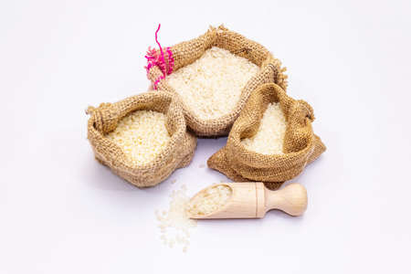 Assorted three types of rice isolated on white background. A traditional ingredient in healthy food preparation. Wooden scoop and handmade sacksの写真素材