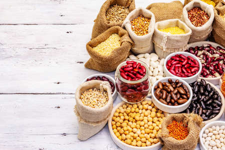 Assorted different types of beans and cereals grains. Set of indispensable sources of protein for a healthy lifestyle. White wooden boards backgroundの写真素材