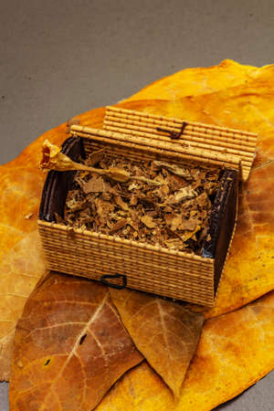 Shredded tobacco in a wicker chest. High quality cured big leaves to make cigars. Black stone concrete background, close upの写真素材