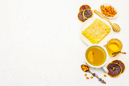 Healing sea-buckthorn tea delicious aromatic full of vitamin and microelements. Honey, fresh berries, honeycomb and lemon. White putty background, top viewの写真素材