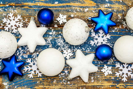 Christmas or New Year festive background. White and blue Christmas balls and stars, snowflakes and scattered glitter with artificial snow. Vintage wooden boards in blue tones, top viewの写真素材