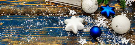 Christmas or New Year festive background. White and blue Christmas balls and stars, snowflakes and scattered glitter with artificial snow. Vintage wooden boards in blue tones, banner formatの写真素材
