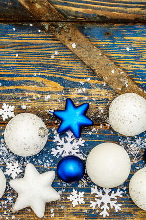 Christmas or New Year festive background. White and blue Christmas balls and stars, snowflakes and scattered glitter with artificial snow. Vintage wooden boards in blue tones, top viewの写真素材