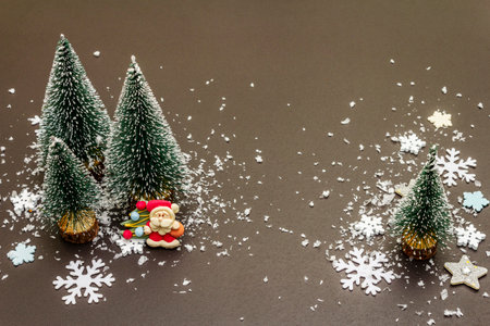 Small decorative Christmas trees with New Year's decor. Santa Claus, snowflakes on black stone concrete background, copy spaceの写真素材