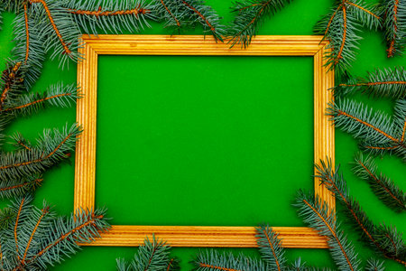 Christmas background with fresh Xmas tree branches and wooden frame on green background. Greeting card concept, top viewの写真素材