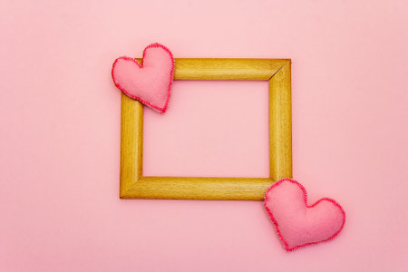 Valentine Day or Wedding concept with soft felt hearts and wooden frame. Light pink background, flat layの写真素材