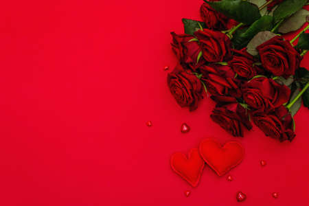 Bouquet of fresh burgundy roses and soft felt hearts on a matte red foamiran background. Fragrant...